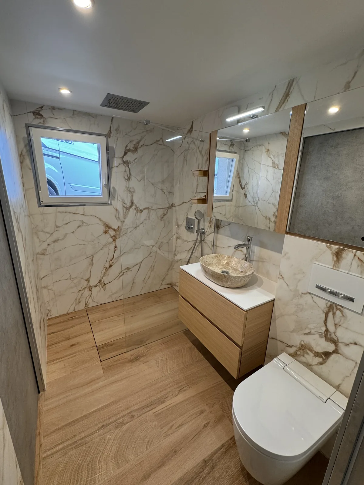 Salle de bains en marbre et bois avec douche et meuble vasque